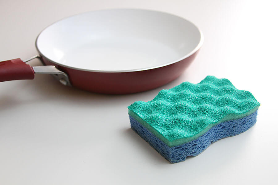 Hand cleaning the non stick pan with handy dish washing sponge